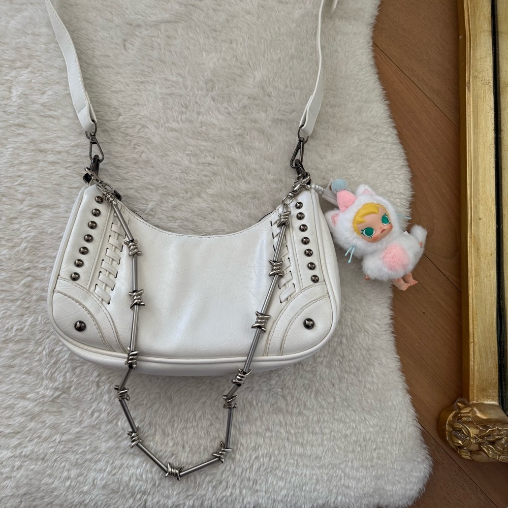 The Kript white studded purse with barbed wire chain and Baby Molly charm
